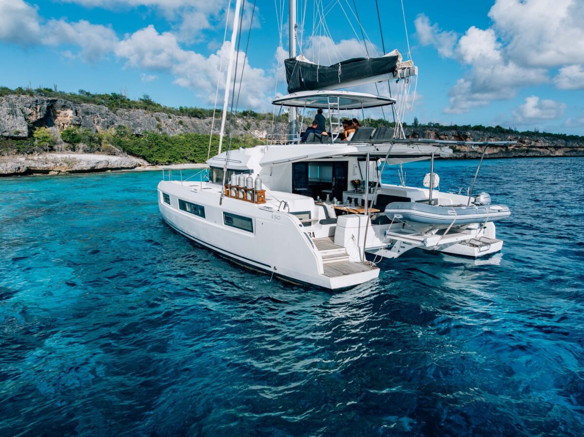 Lagoon catamaran at anchor near Bonaire's cliffs with alfresco dining set on deck