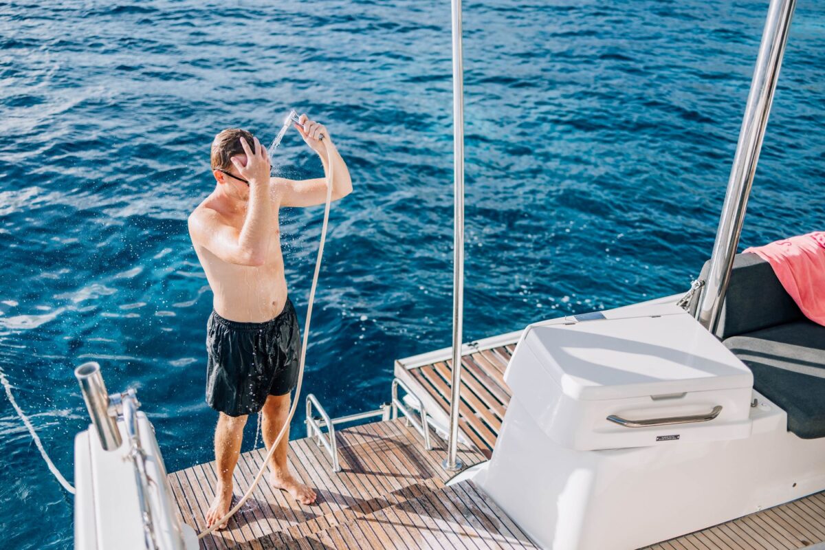Guest rinsing off at the heated deck shower on a private catamaran charter