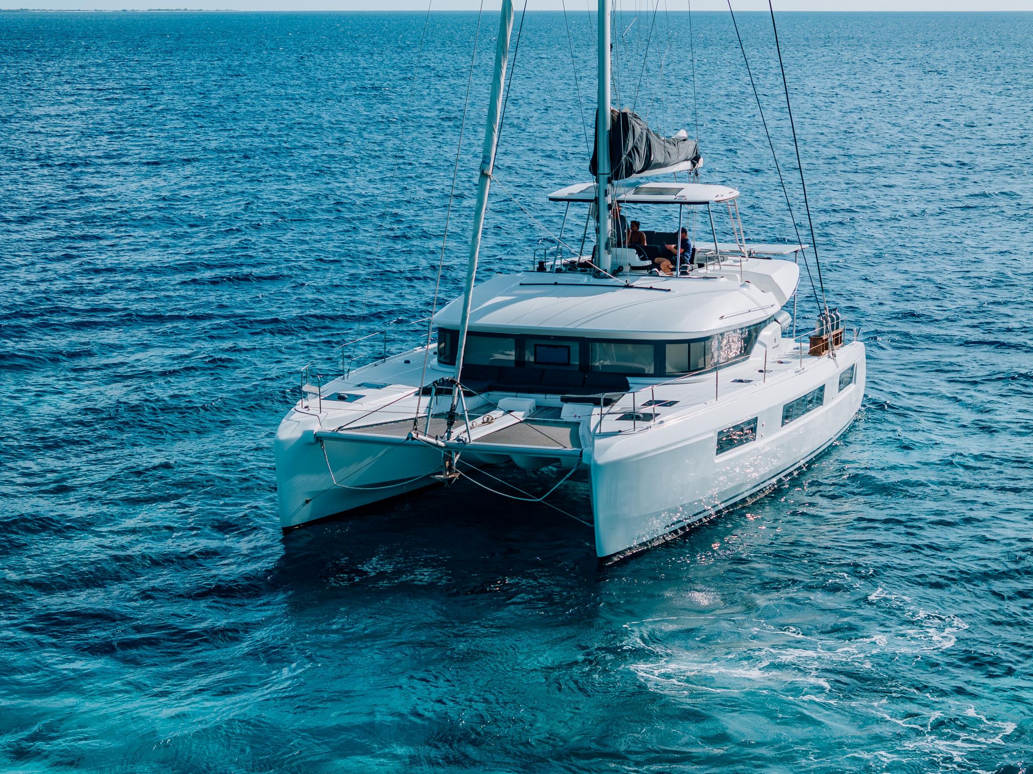 multi-day private catamaran under sail with guests relaxing onf the flybridge