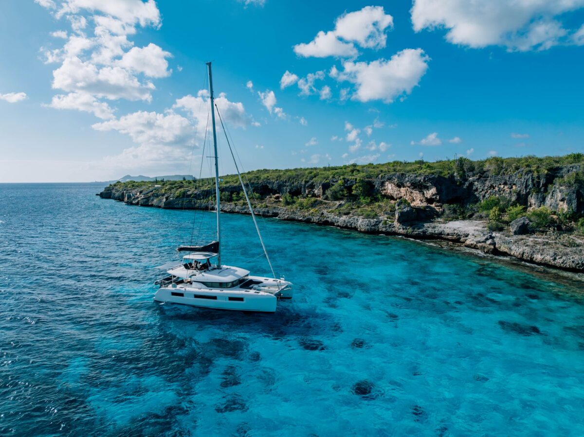 Private catamaran sailing along Bonaire's cliff coastline, alternate view