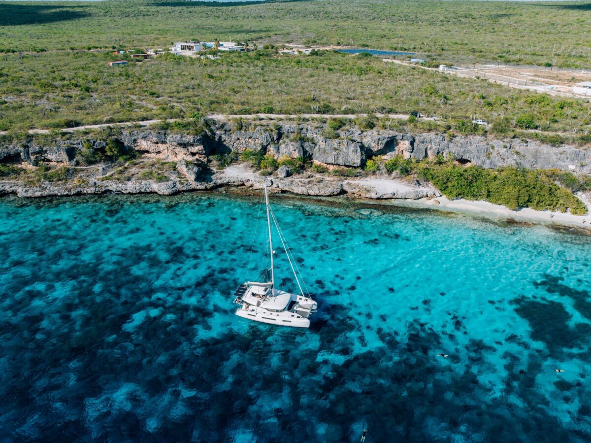 Lagoon catamaran at anchor near Bonaire's cliffs with alfresco dining set on deck
